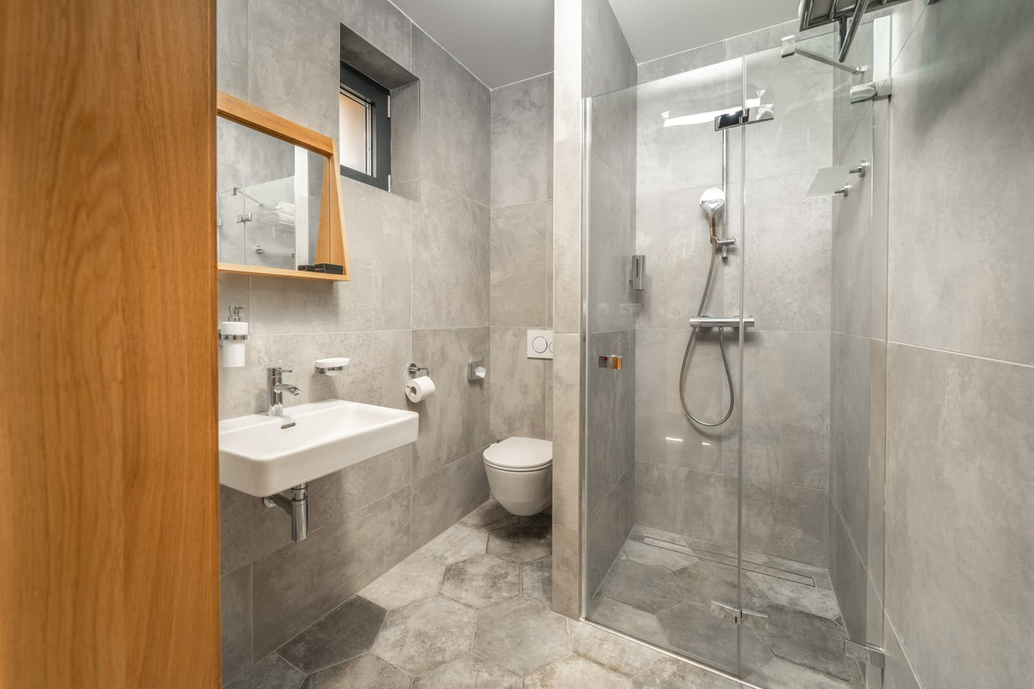 Modern grey tiled bathroom featuring minimalist hinged glass shower door, reference layout for planning 50 to 54 inch shower door fit.