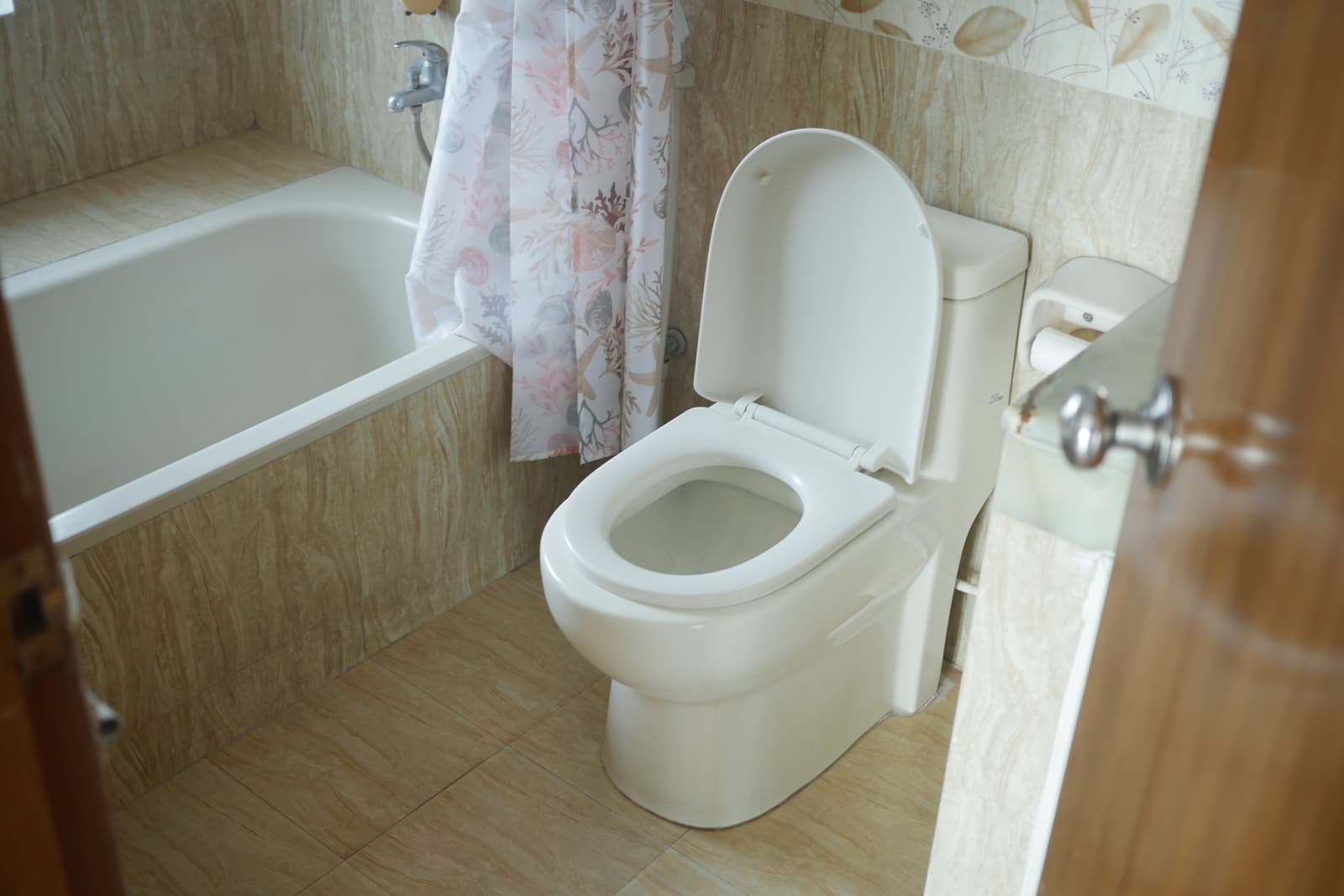 White two-piece floor-mounted toilet installed inside a classic home bathroom with bathtub, representing the popular standard residential toilet option.