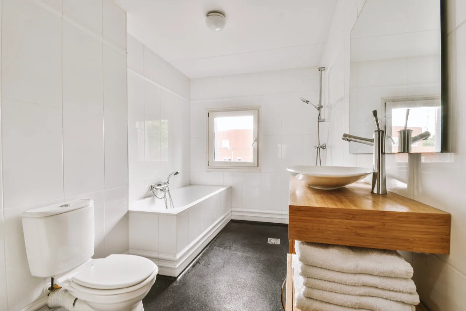 A clean white bathroom with a toilet, bathtub, and vessel sink, showcasing antimicrobial ceramic glaze benefits.