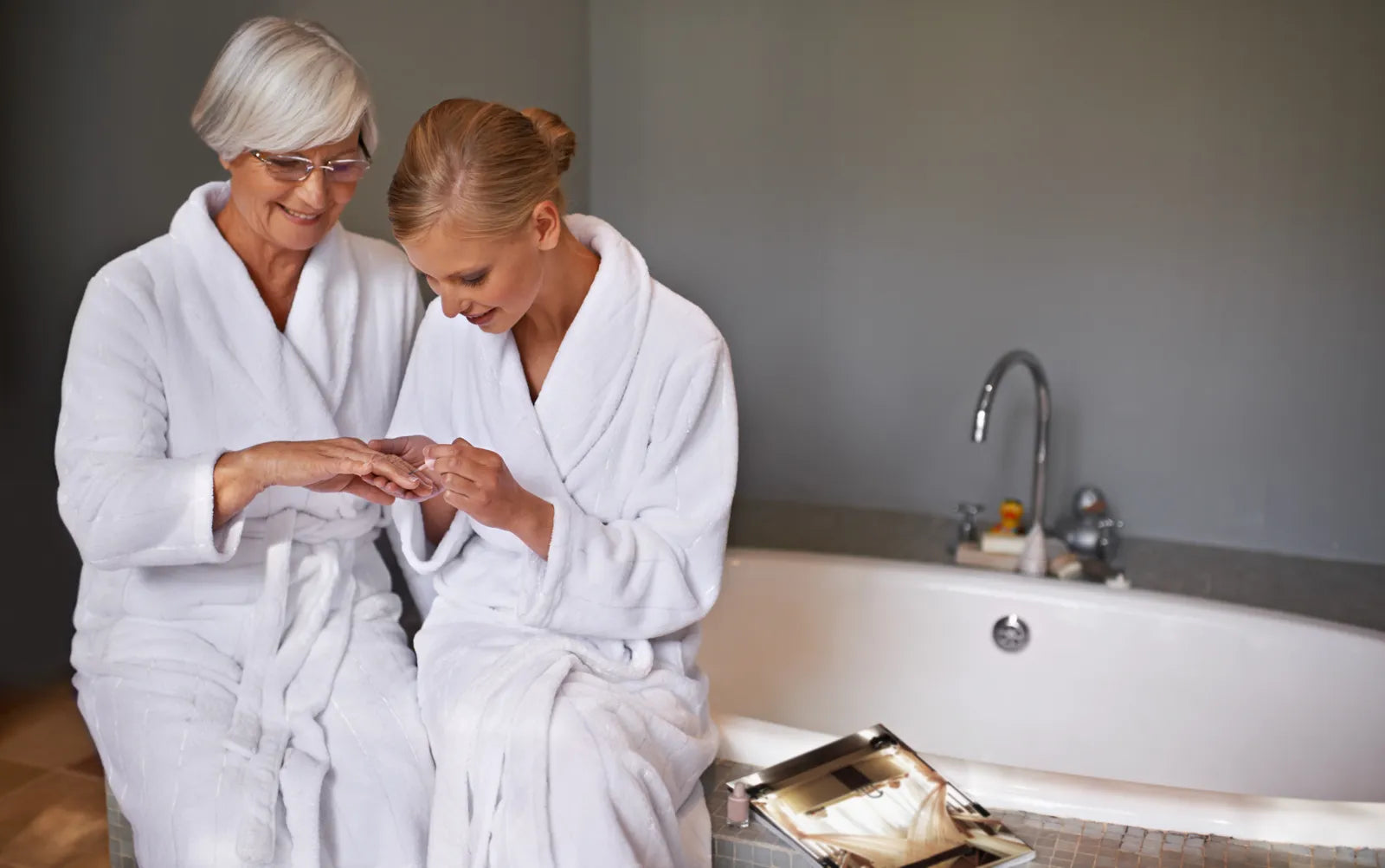 Seniors relax in bathrobes by a renovated, senior-friendly bathtub.