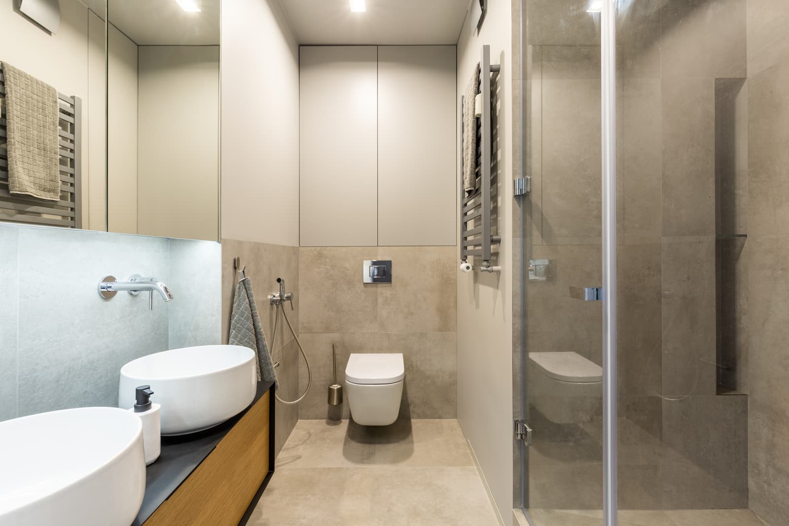 Contemporary neutral-toned bathroom with clear glass shower door, illustrating how glass shower enclosures look in homes with hard water.