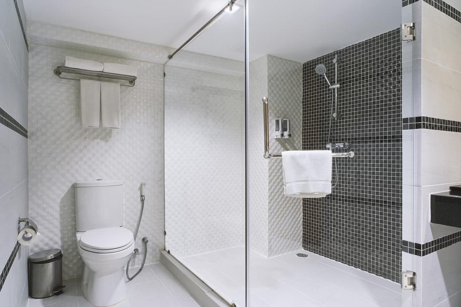This clean modern bathroom features a sliding glass shower enclosure with a metal bottom door track.