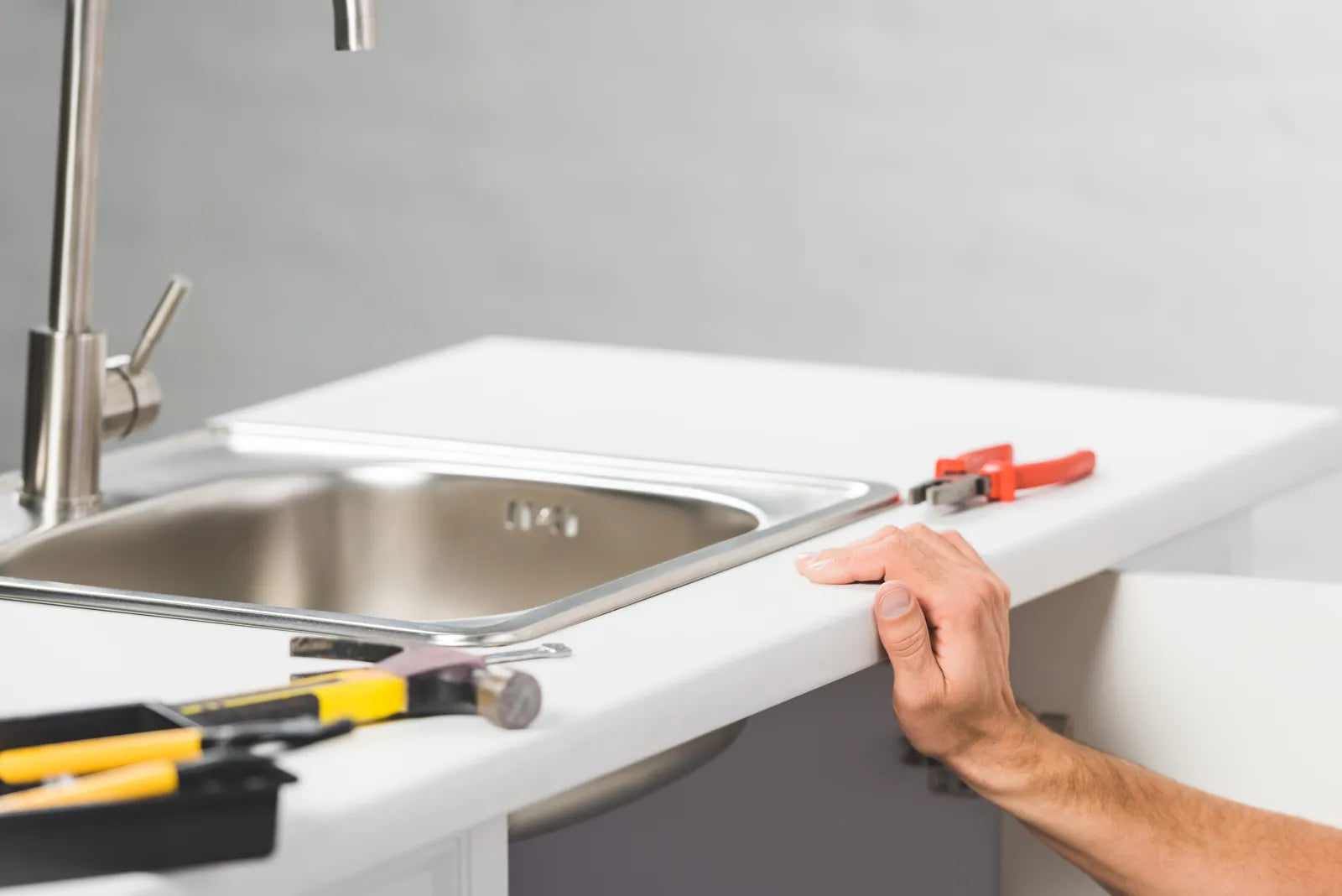 A worker prepares tools to accurately measure the opening for a new kitchen sink.