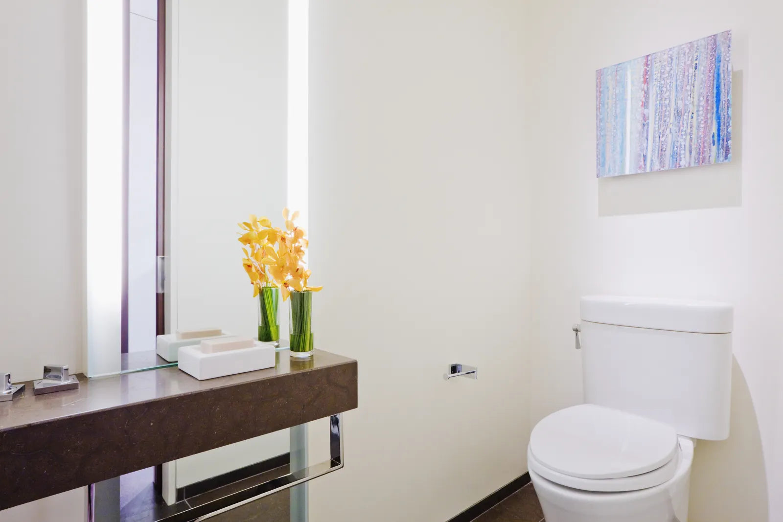 A clean, modern bathroom featuring a white low-flow toilet and a sleek vanity with fresh flowers.