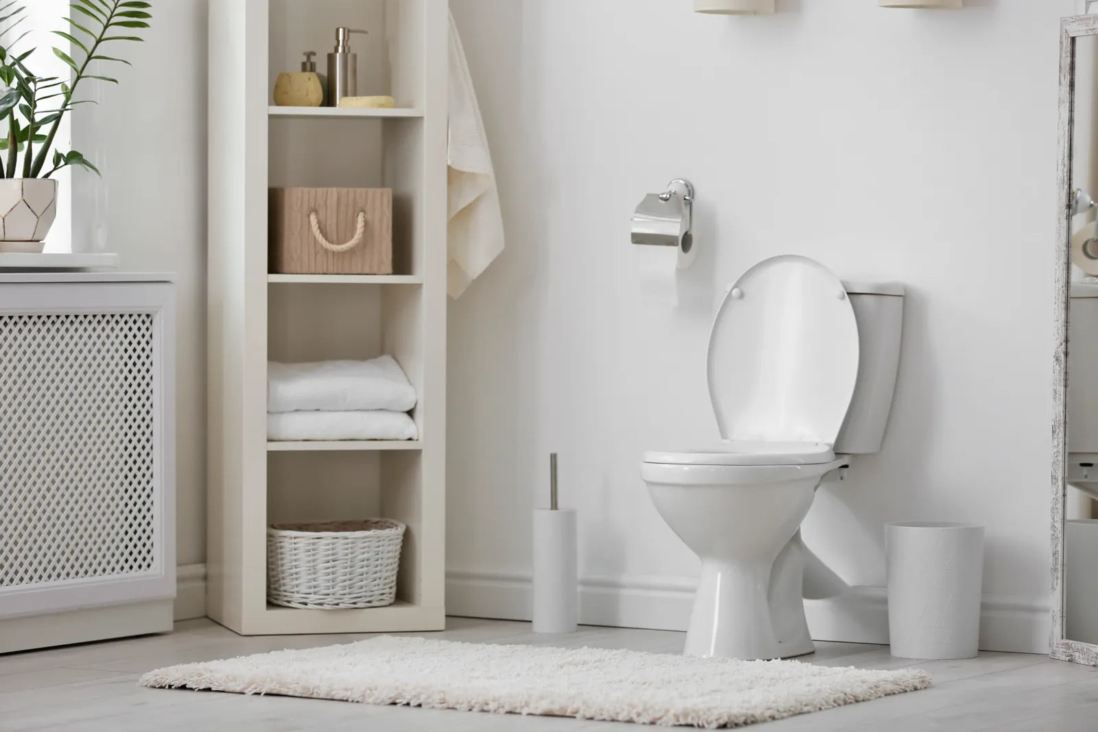 A bright, minimalist bathroom with a white toilet, open shelving, and clean decor.