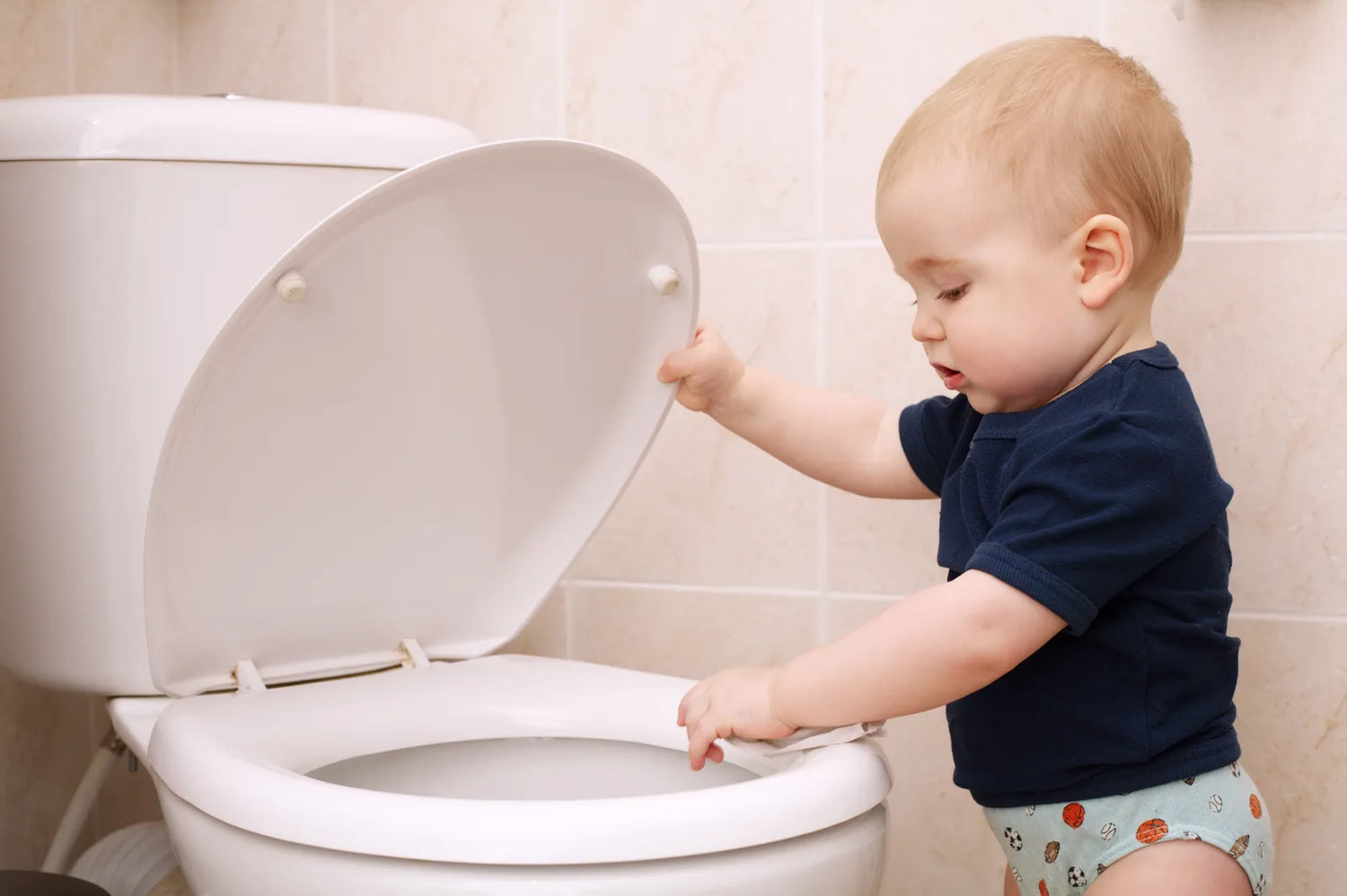 A toddler interacting with a standard height toilet in a bathroom, demonstrating the usability of lower toilets for young children.