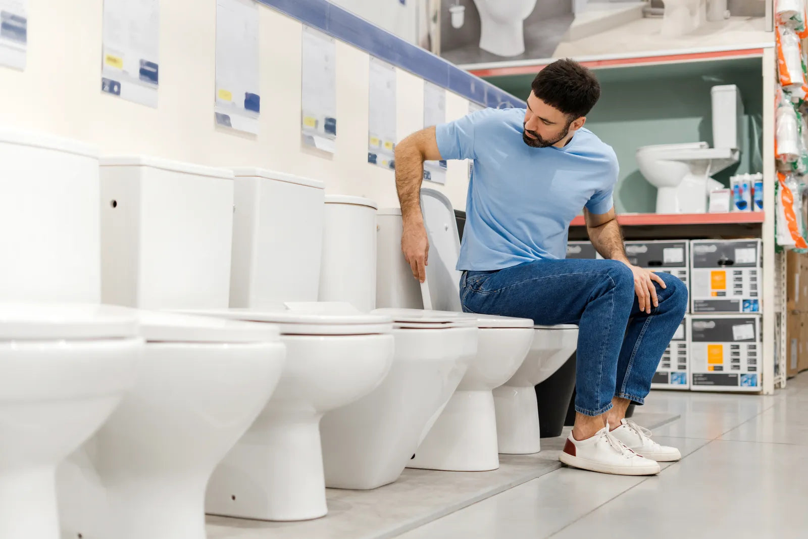 A man tests a one-piece toilet in a store, evaluating fit for its flange installation.