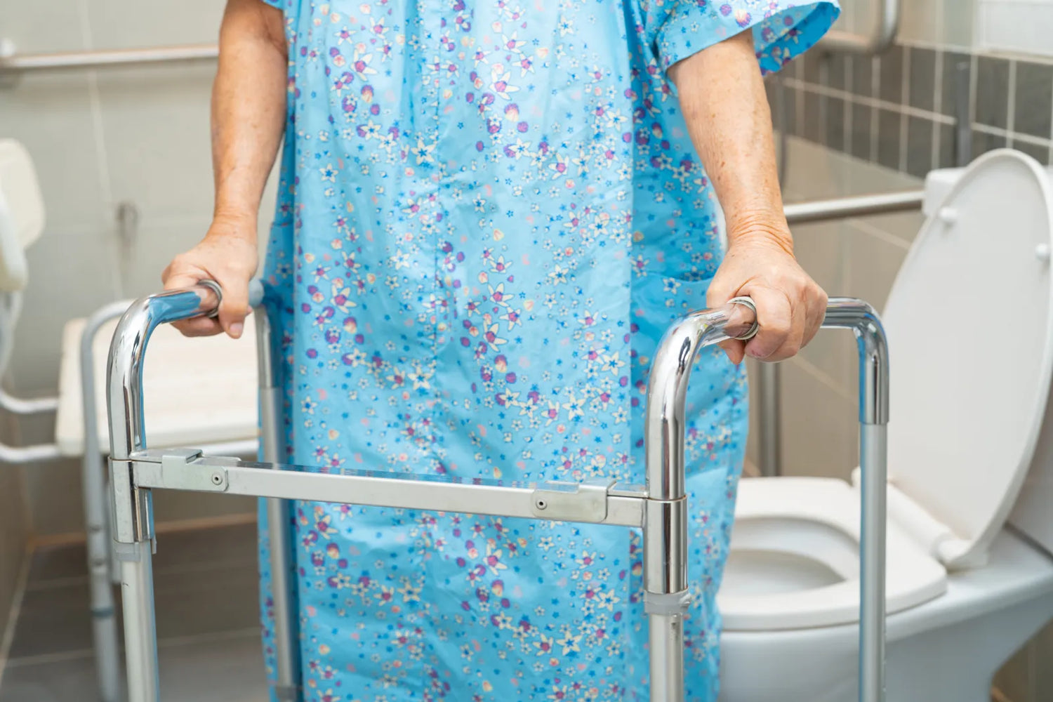 Elderly adult using mobility aid next to senior safety toilet with support grab bars