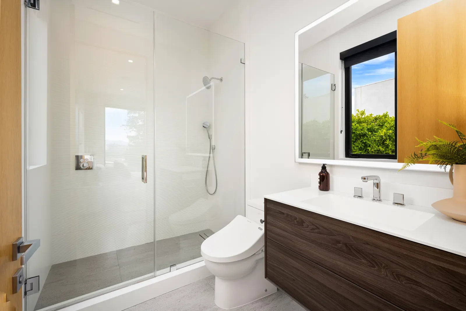 A modern bathroom features a WaterSense smart toilet next to a glass shower.
