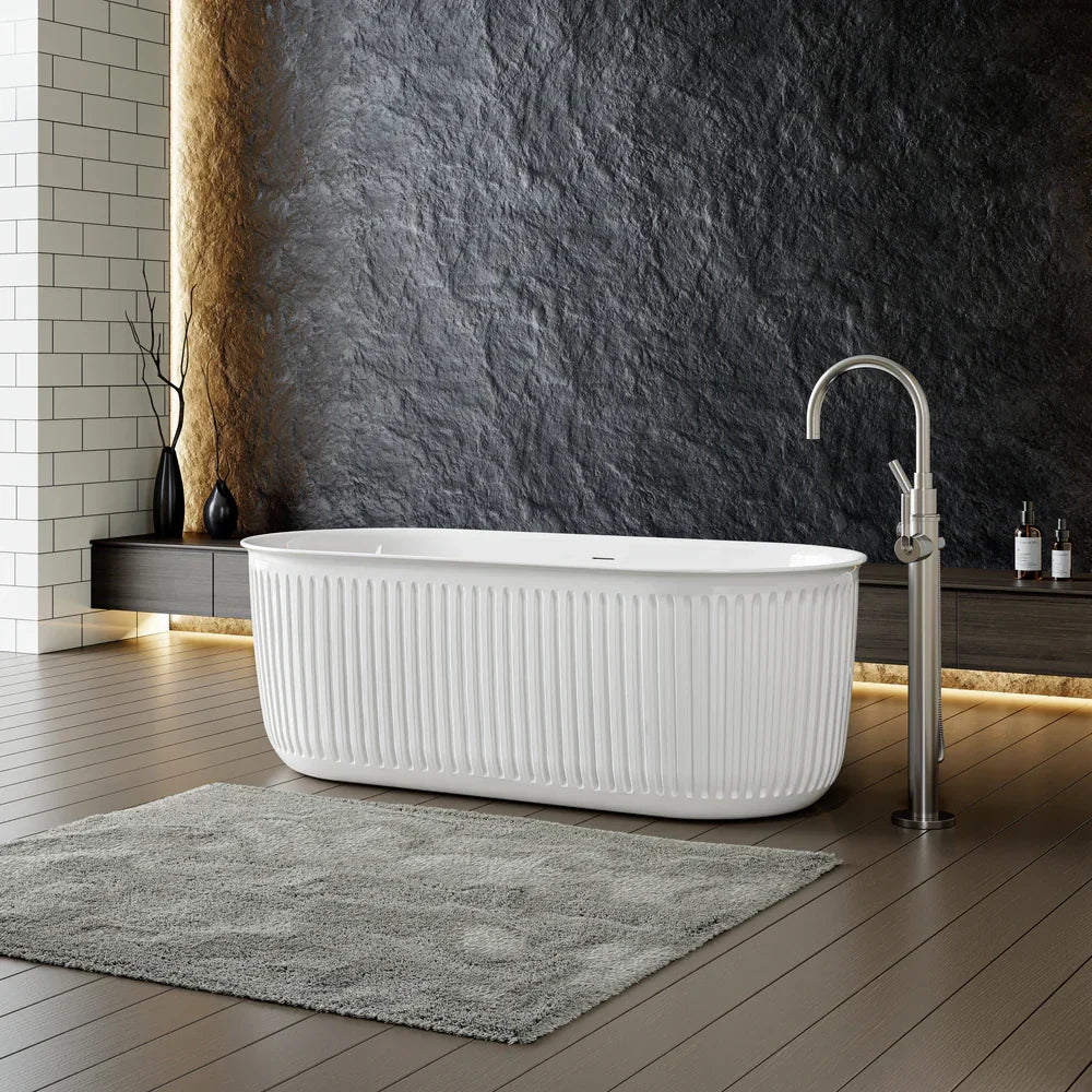 White freestanding soaking tub with vertical fluting, paired with a sleek floor-mounted faucet, creates a spa-like focal point in a modern small master bath.