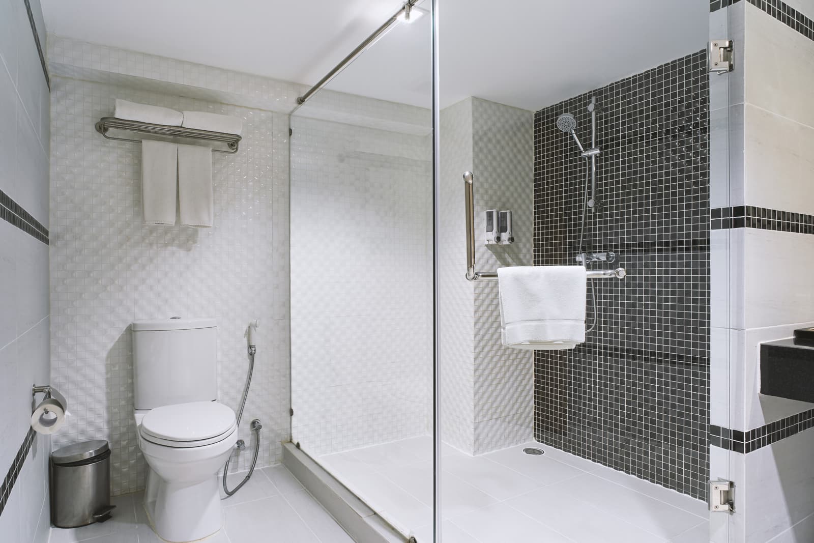 This contemporary hotel bathroom features a sliding glass shower door installed within a tiled shower space.