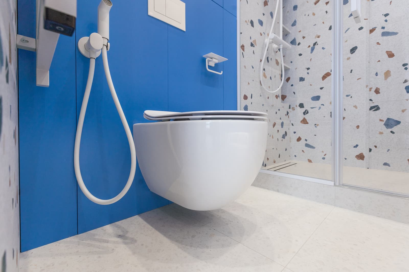 Sleek white wall-hung smart toilet installed inside a contemporary blue bathroom, representing premium integrated smart toilet designs for renovation projects.