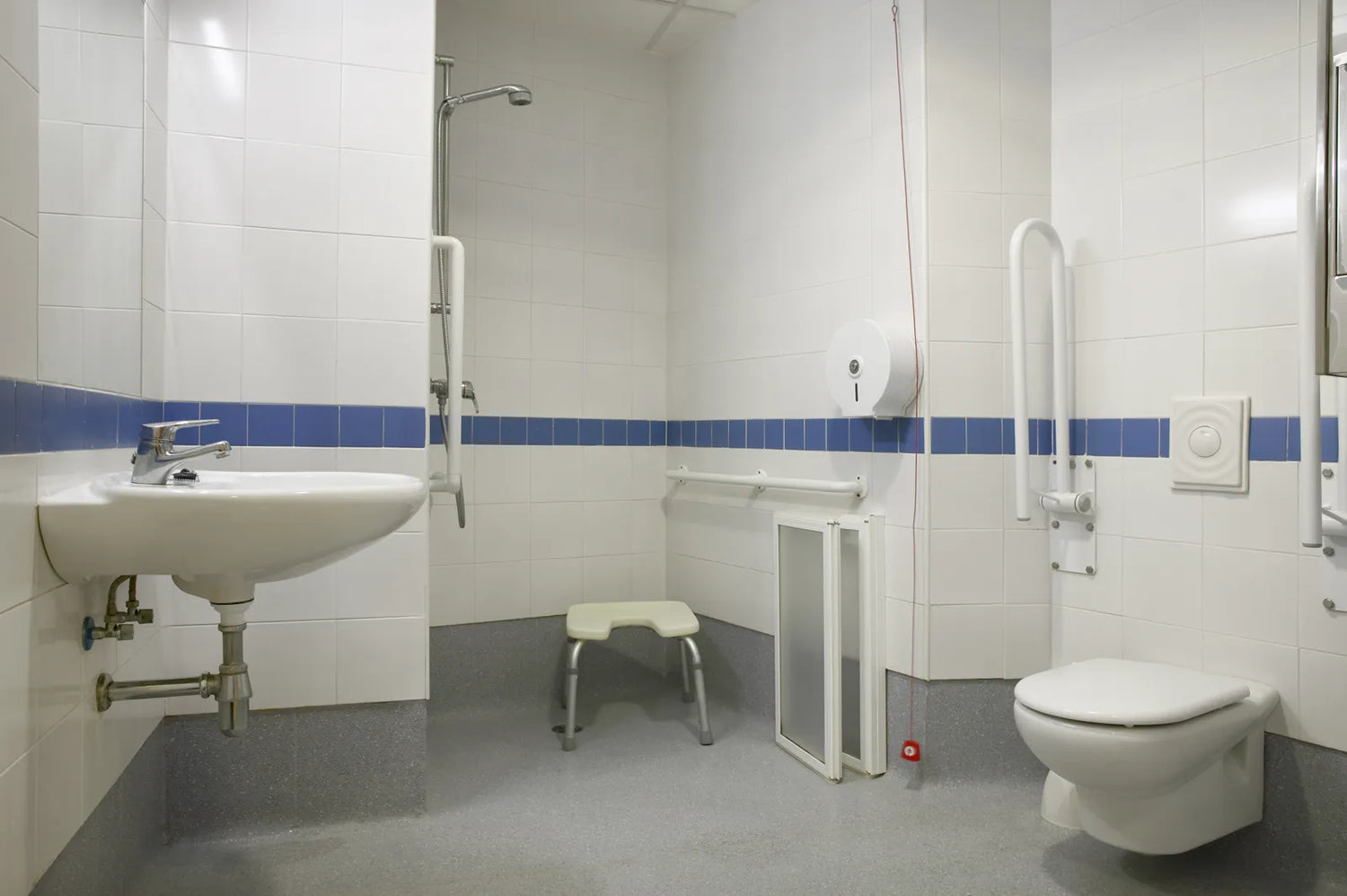 Accessible bathroom with grab bars, shower seat, and wide layout, meeting full ADA compliance requirements.
