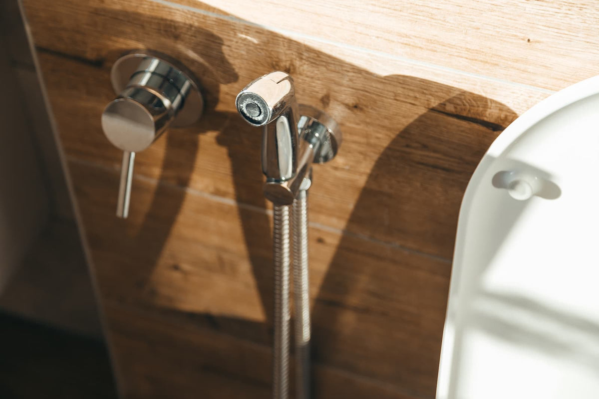 Extended bidet nozzle beneath an open toilet seat