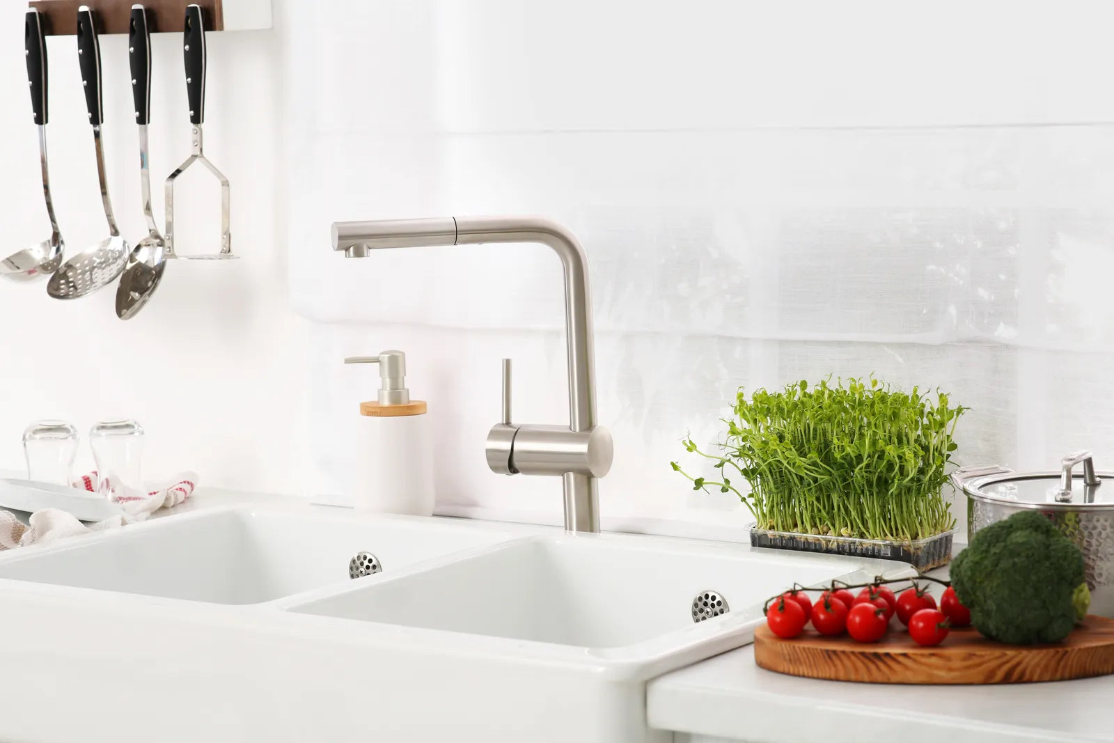 Bright white fireclay double-basin sink with a modern faucet, highlighting its classic farmhouse style.