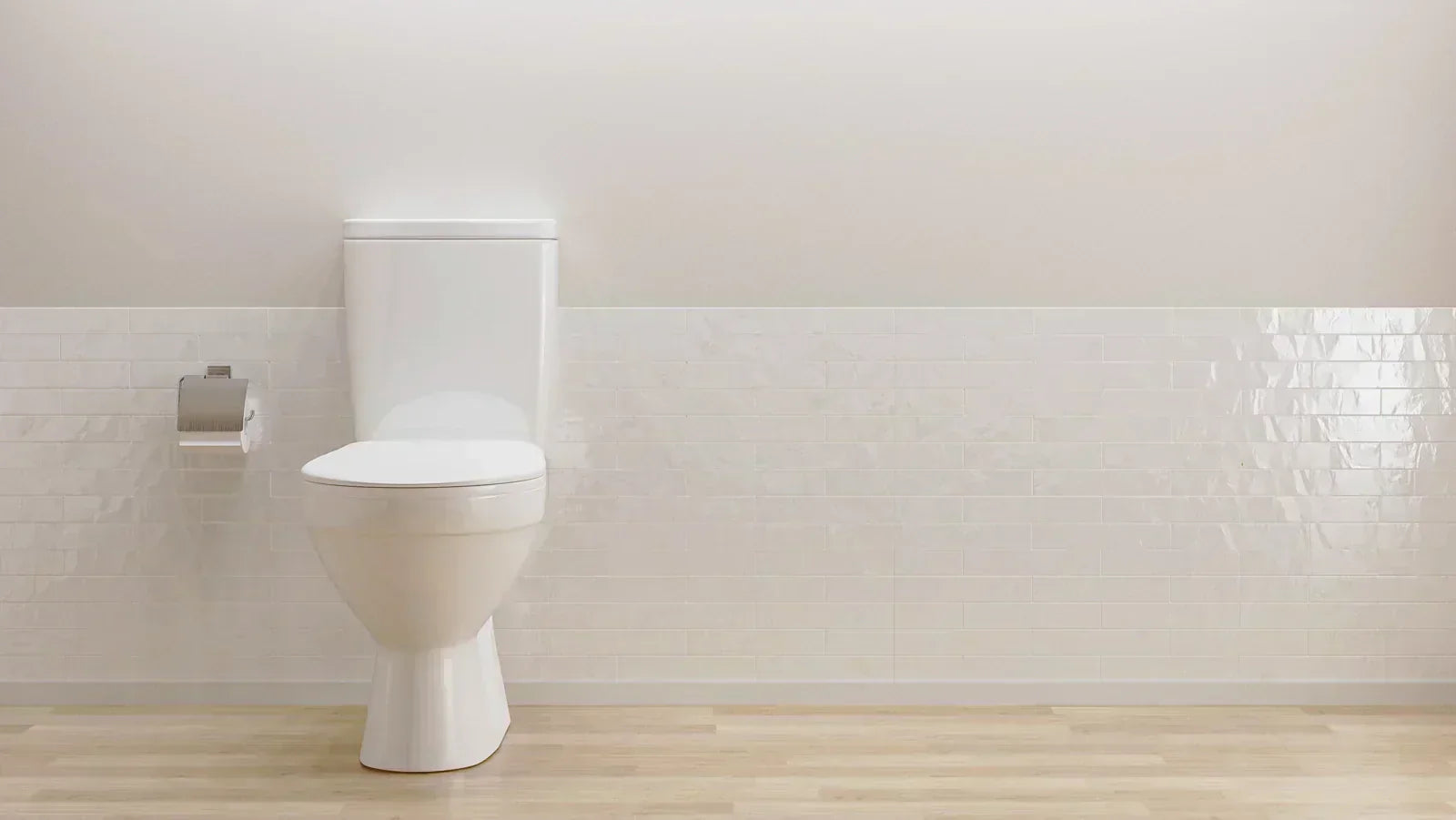 A sleek white toilet sits against a wall with white subway tiles and light wood flooring.