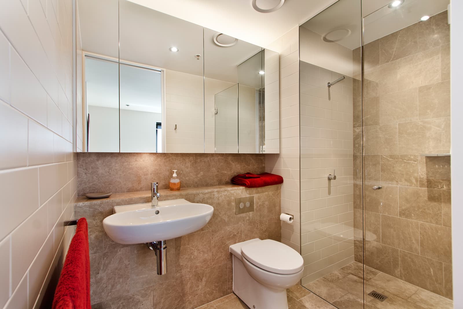 Contemporary family bathroom featuring frameless inline shower enclosure with polished chrome hardware alongside matching basin fixtures.