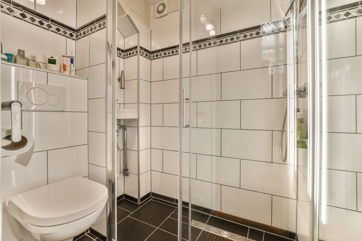 Small residential bathroom featuring framed sliding shower enclosure fitted with polished chrome metal hardware and vertical pull handle.
