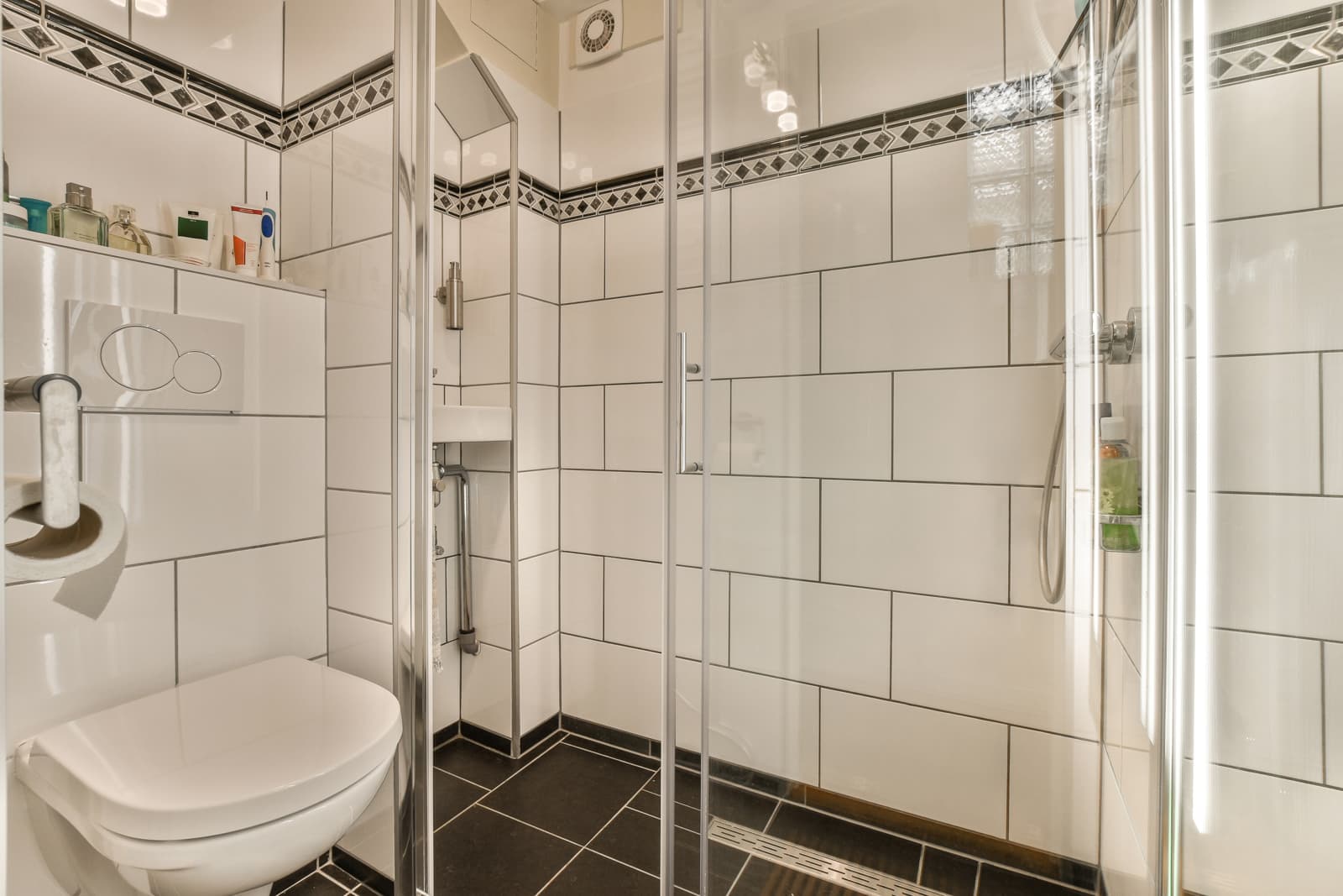 Small residential bathroom featuring framed sliding shower enclosure fitted with polished chrome metal hardware and vertical pull handle.