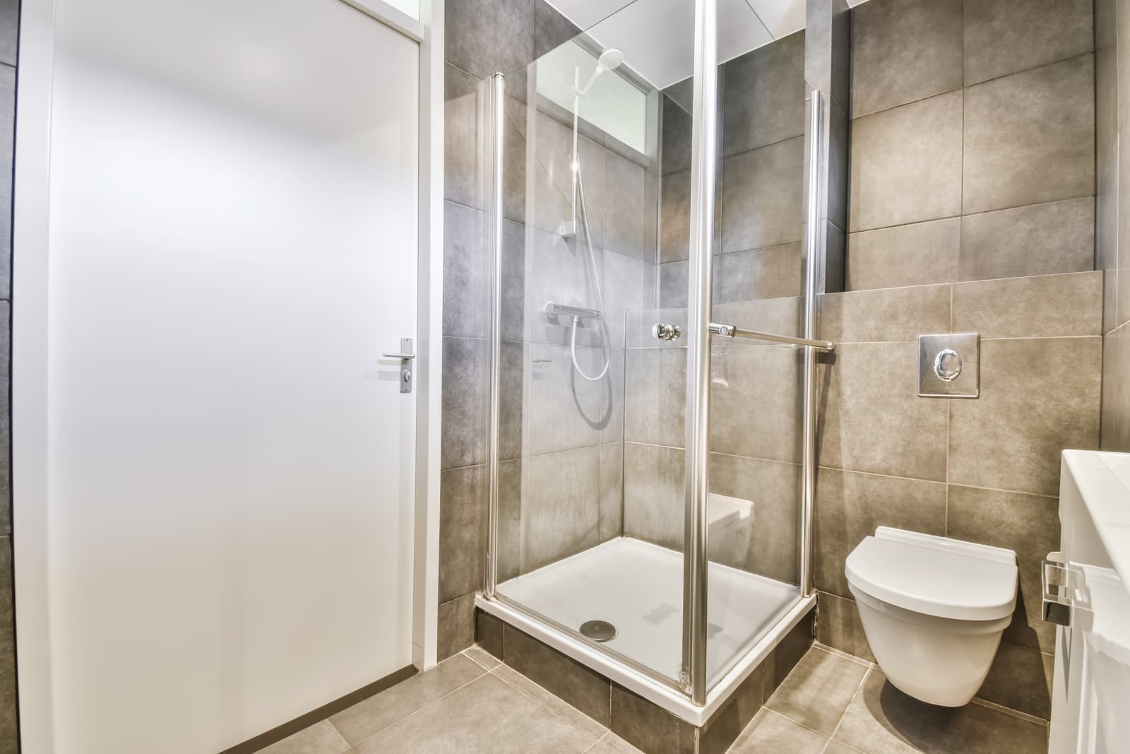 Contemporary tiled bathroom featuring a framed sliding glass shower door, showing typical sliding shower enclosure layout in residential restroom.