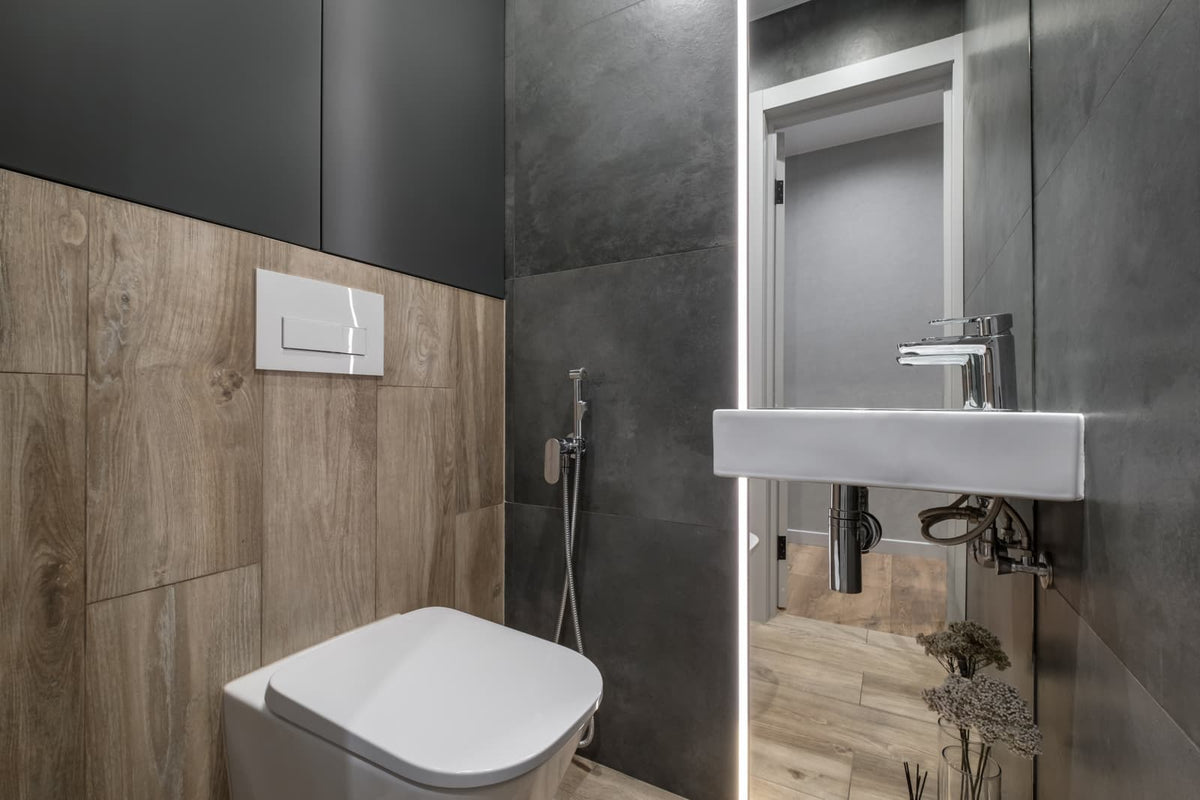 Modern bathroom with a sleek toilet, wall-mounted flush plate, and handheld bidet sprayer