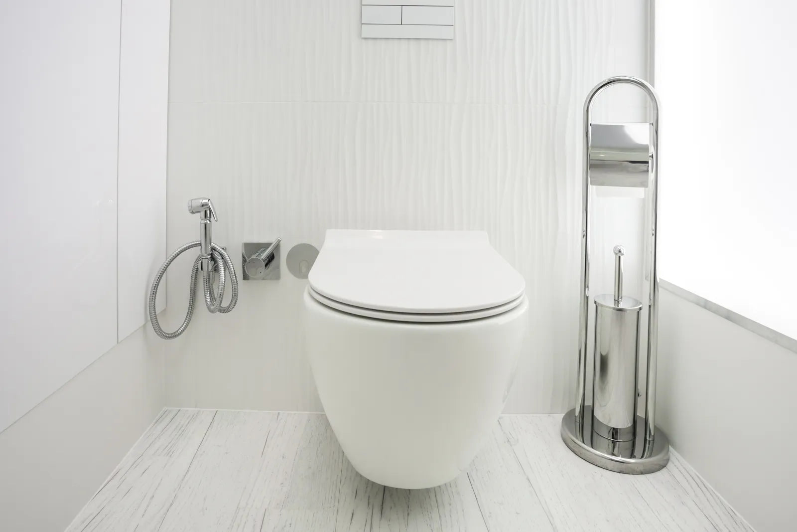 A modern wall-mounted tankless toilet is installed in a bright bathroom.