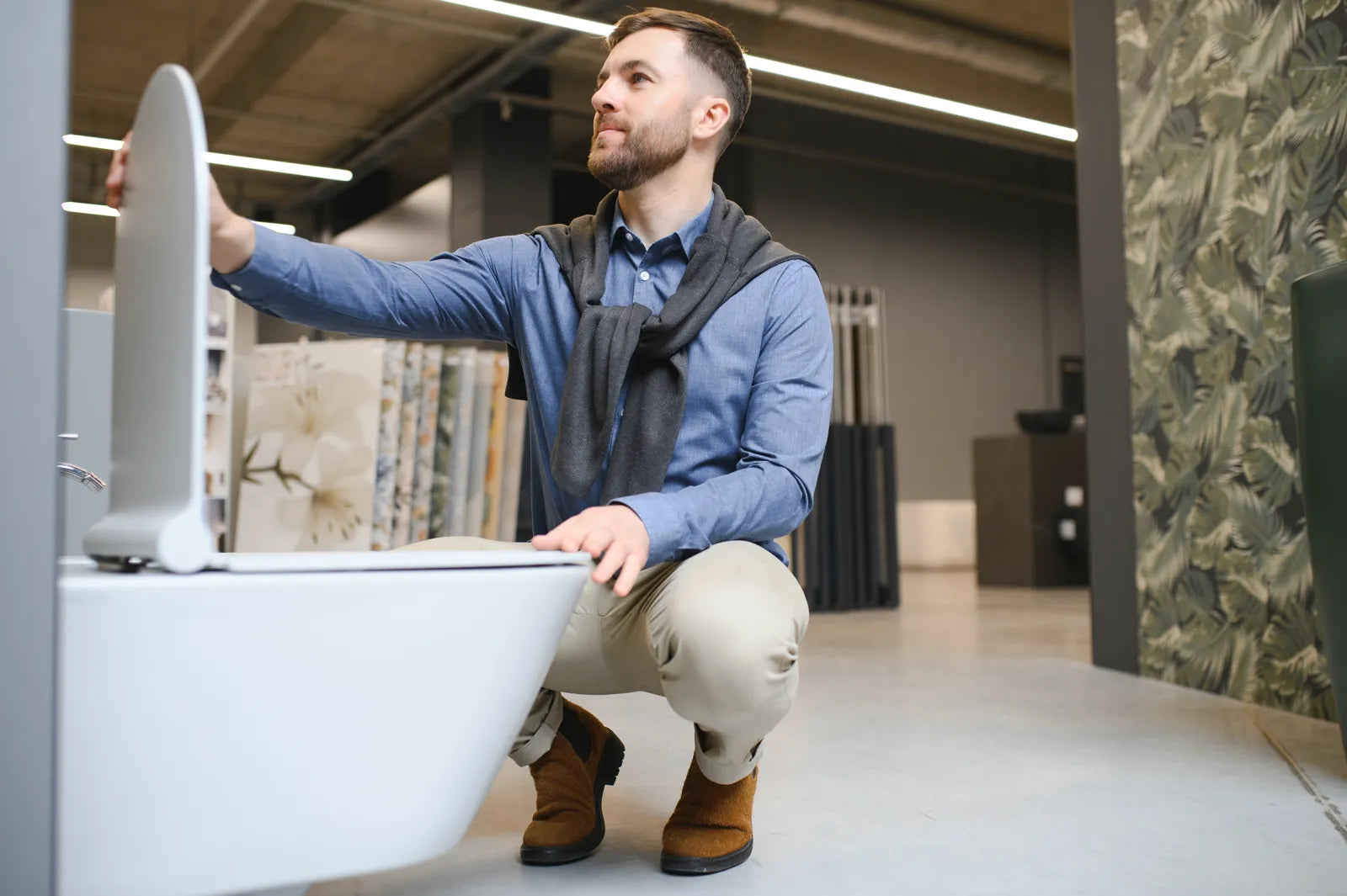 A man inspects a smart toilet in a showroom, checking for potential leak points.